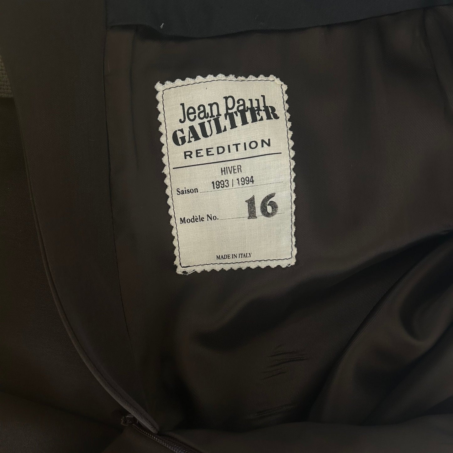 Label detail of the 1993/94 Hiver Re Edition Collection Jean Paul Gaultier wool pencil skirt, featuring 'Jean Paul Gaultier Re Edition,' 'Hiver,' 'Saison 1993/1994,' and 'Made in Italy' text. A collectible piece from the iconic designer's archive.