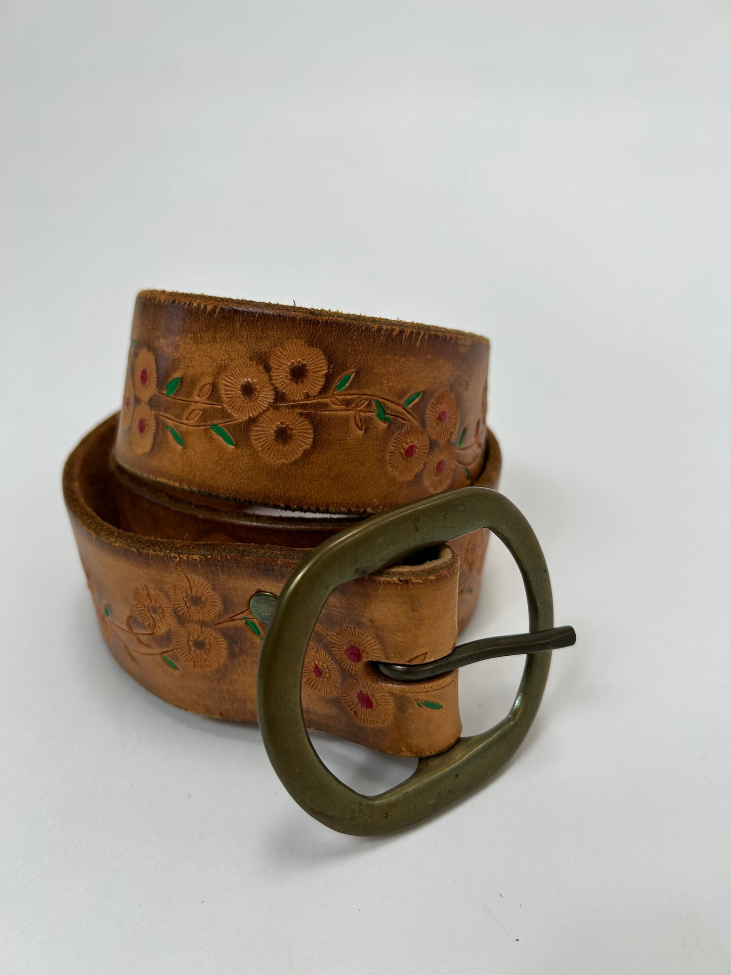 Close-up of a vintage 1970s floral belt, featuring embossed flower patterns with colorful details and a brass buckle, showcasing retro craftsmanship and timeless design.