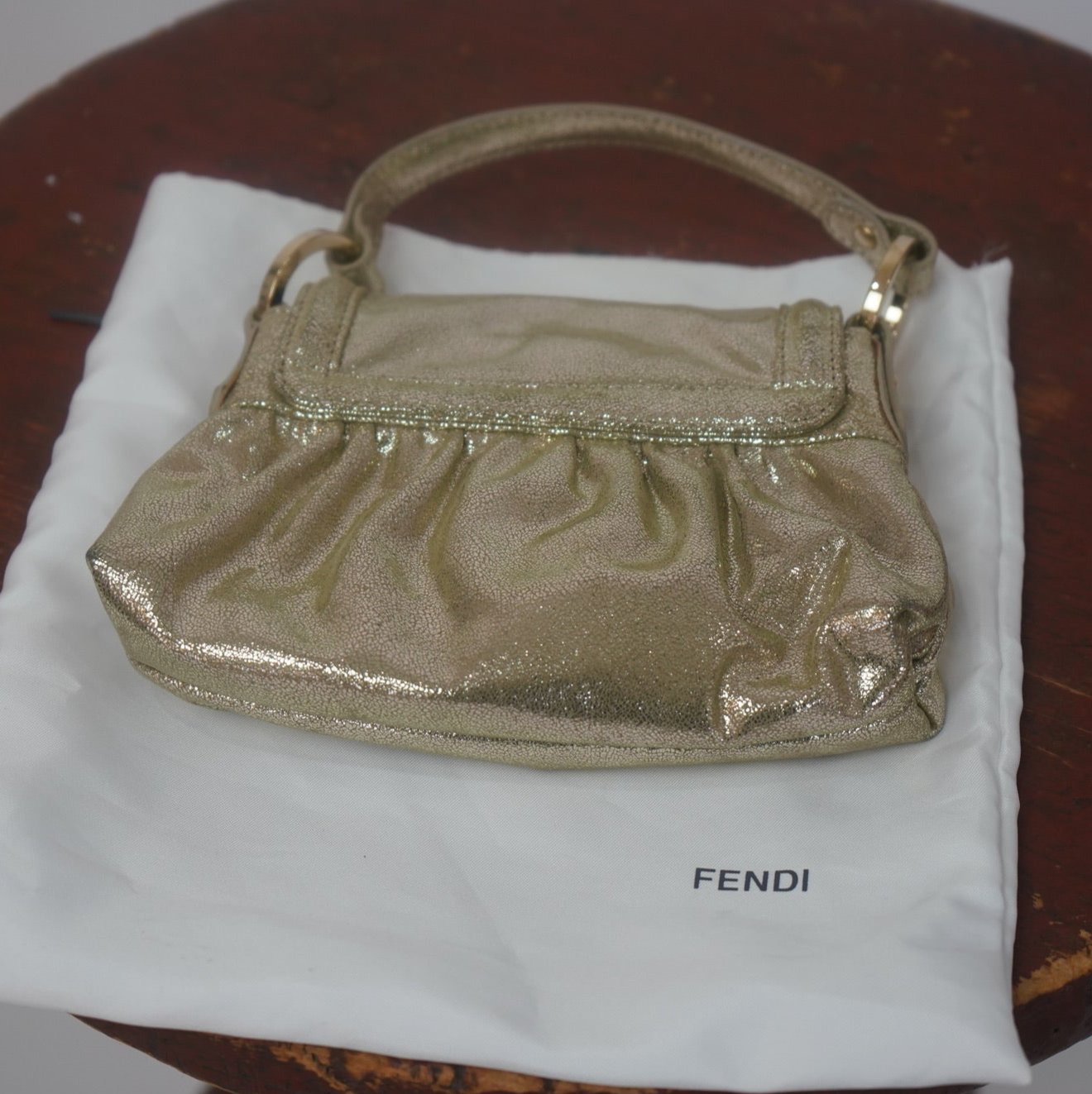 2004 Fendi Metallic Napa Mini Chef Shoulder Bag in gold displayed on a branded Fendi dust bag, showcasing its elegant ruched design and luxurious craftsmanship.