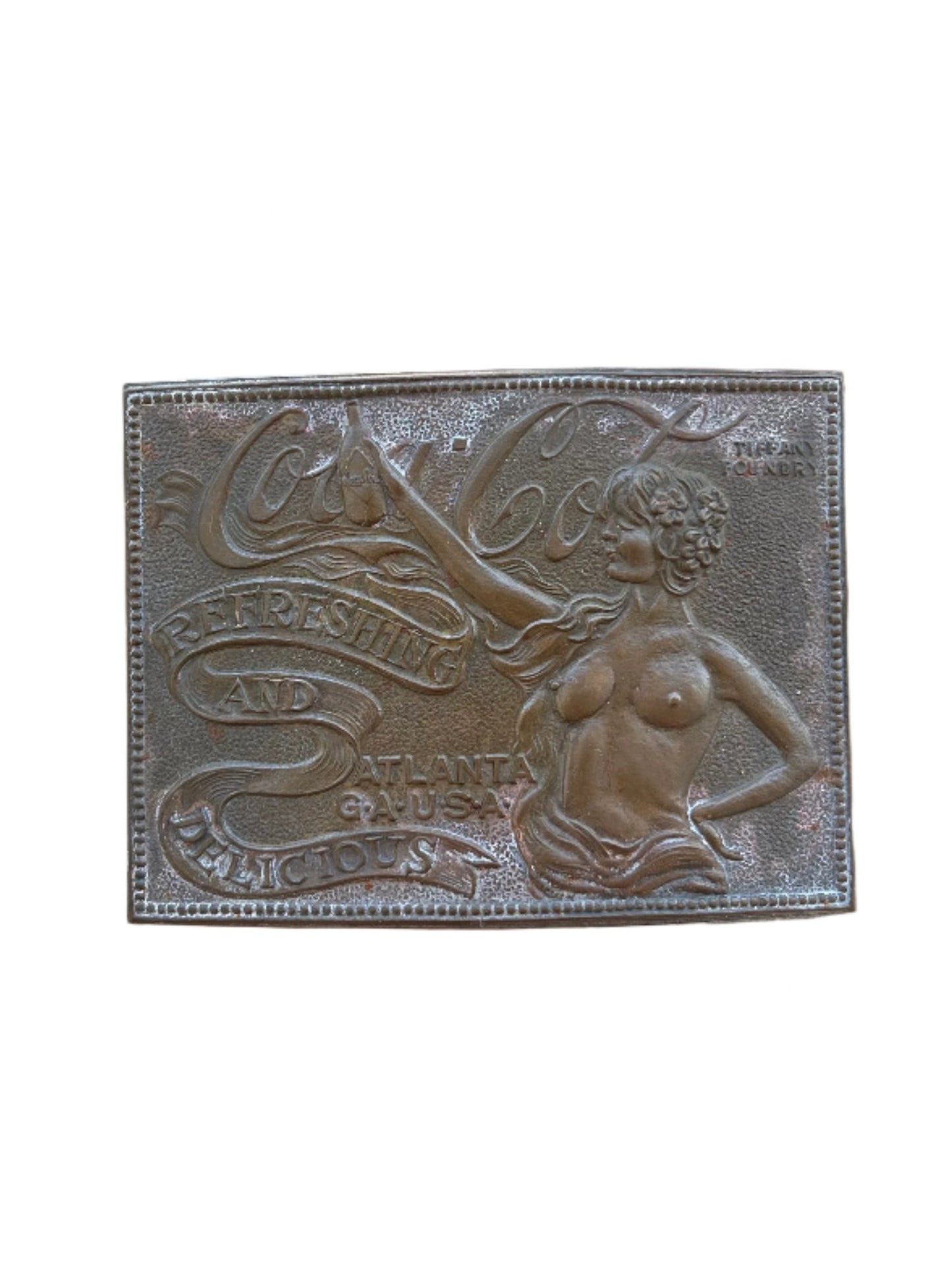 Vintage 1970s Coca-Cola belt buckle by Tiffany & Co., featuring intricate embossed artwork with Coca-Cola branding and 'Refreshing and Delicious' slogan, a rare collectible combining retro charm and fine craftsmanship.
