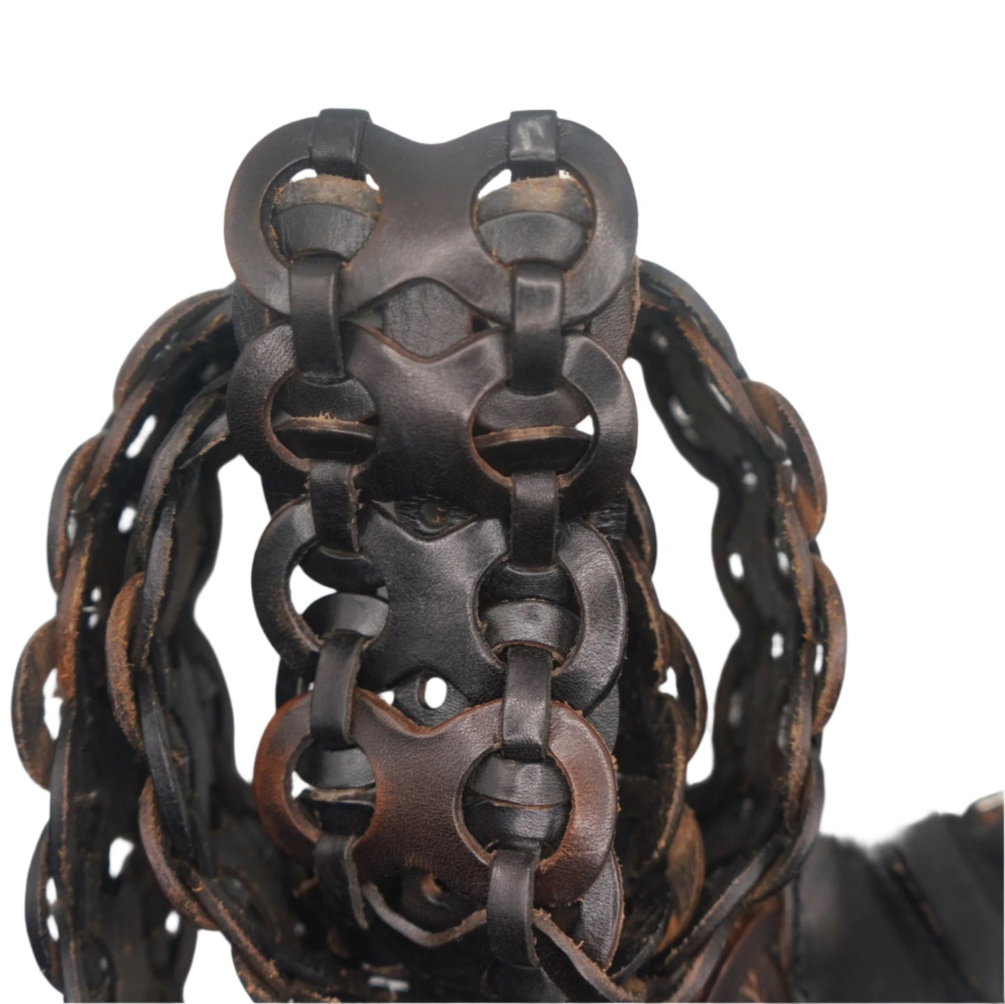 A close-up view of the intricate woven design of a vintage black leather belt. The interlocking loop pattern is highlighted from an overhead angle, showcasing the smooth texture of the leather and the contrasting brown stitching around the edges. The belt is coiled, with a section of the buckle partially visible on the right side.