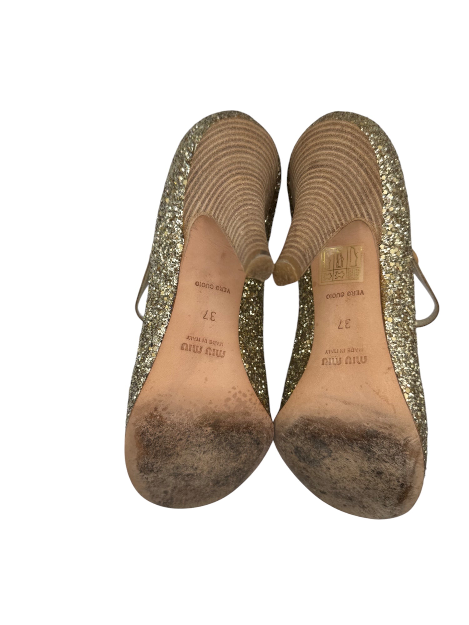 Pair of gold glittery shoes with soles showing wear on a white background