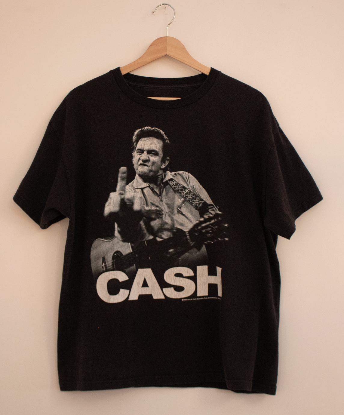 2009 Johnny Cash black graphic t-shirt featuring an iconic image of the legendary musician with his guitar and bold 'CASH' text, embodying vintage band merchandise and classic music style.