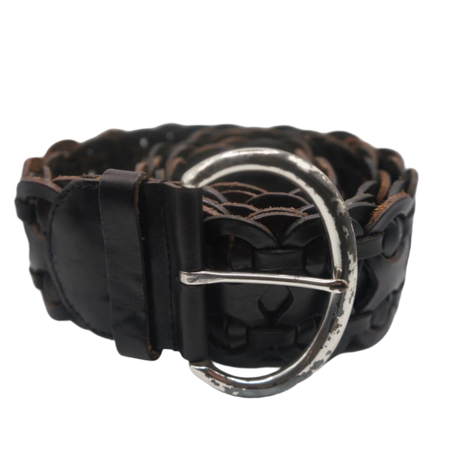 A close-up view of a vintage black leather woven belt with a silver buckle. The belt is coiled, showcasing its intricate braided design and worn, rustic finish. The buckle is circular and slightly tarnished, adding to the belt's aged yet stylish appearance.