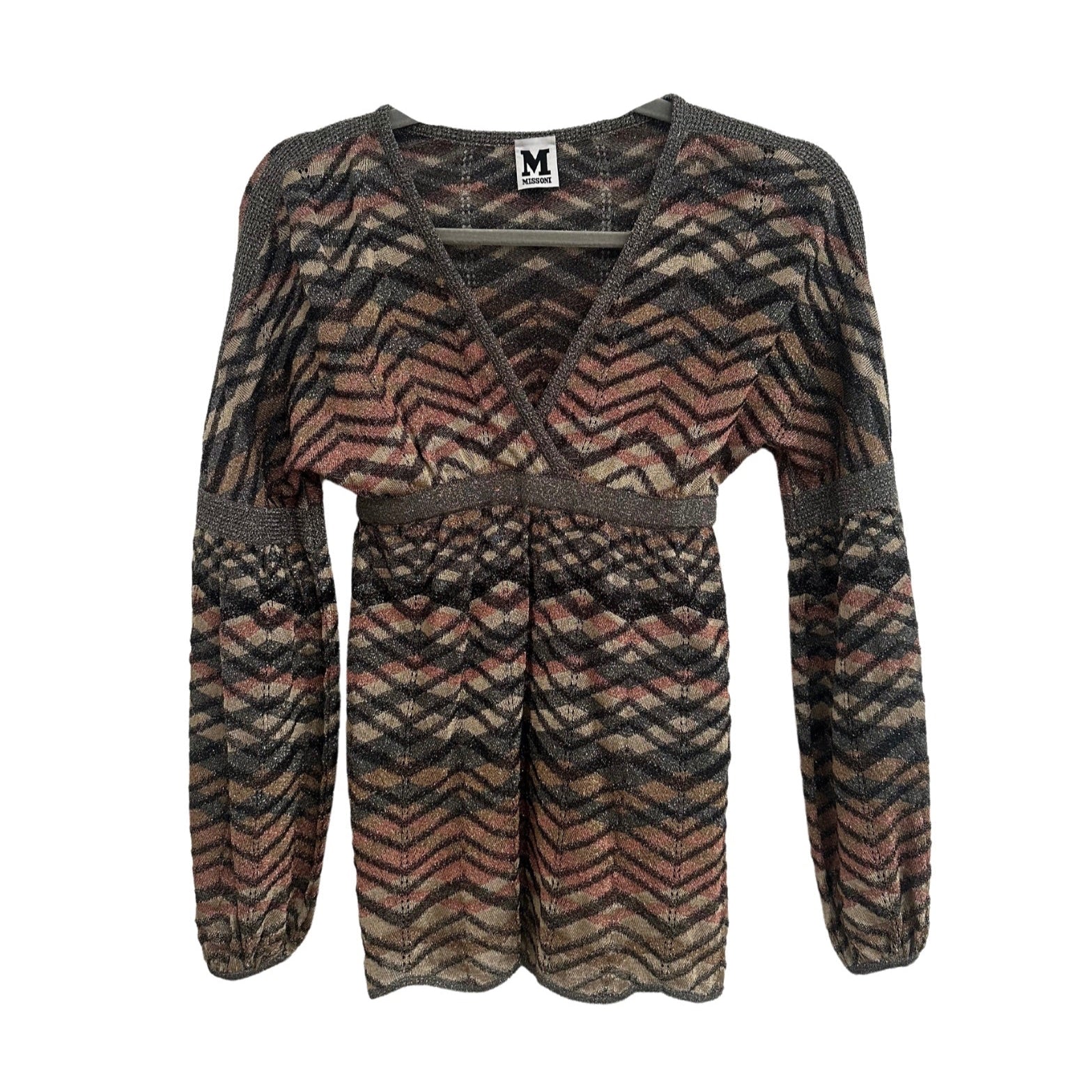 A Missoni 90s balloon sleeve top displayed from the front on a hanger. The top features a deep V-neckline with metallic trim, an empire waist with a fitted band, and long voluminous sleeves that gather at the cuffs. The knit fabric showcases a signature Missoni zigzag pattern in earthy tones of brown, beige, and muted pink with subtle metallic threading. The silhouette is slightly flared at the hem, creating a flowy effect, while the textured knit adds depth to the design.