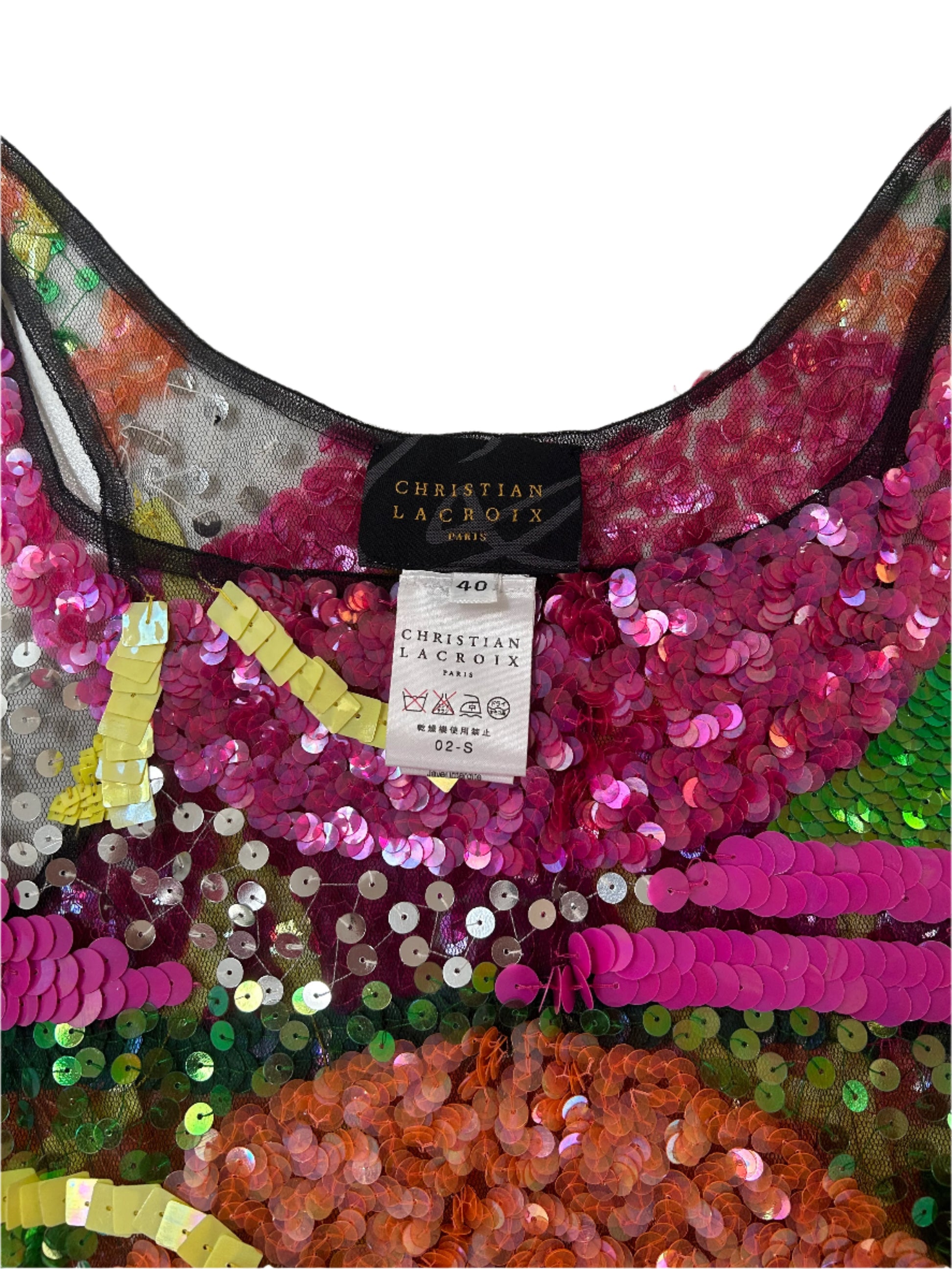 Detailed shot a Christian Lacroix sleeveless top featuring a striking, multicolored sequin design. The intricate embellishments create an abstract pattern of vibrant pinks, greens, oranges, and yellows, set against a sheer black mesh base. The scoop neckline and fitted silhouette highlight its elegant yet playful aesthetic, while the craftsmanship reflects Lacroix’s signature opulent style. This top is a bold statement piece, ideal for special occasions or adding a touch of drama to an ensembl
