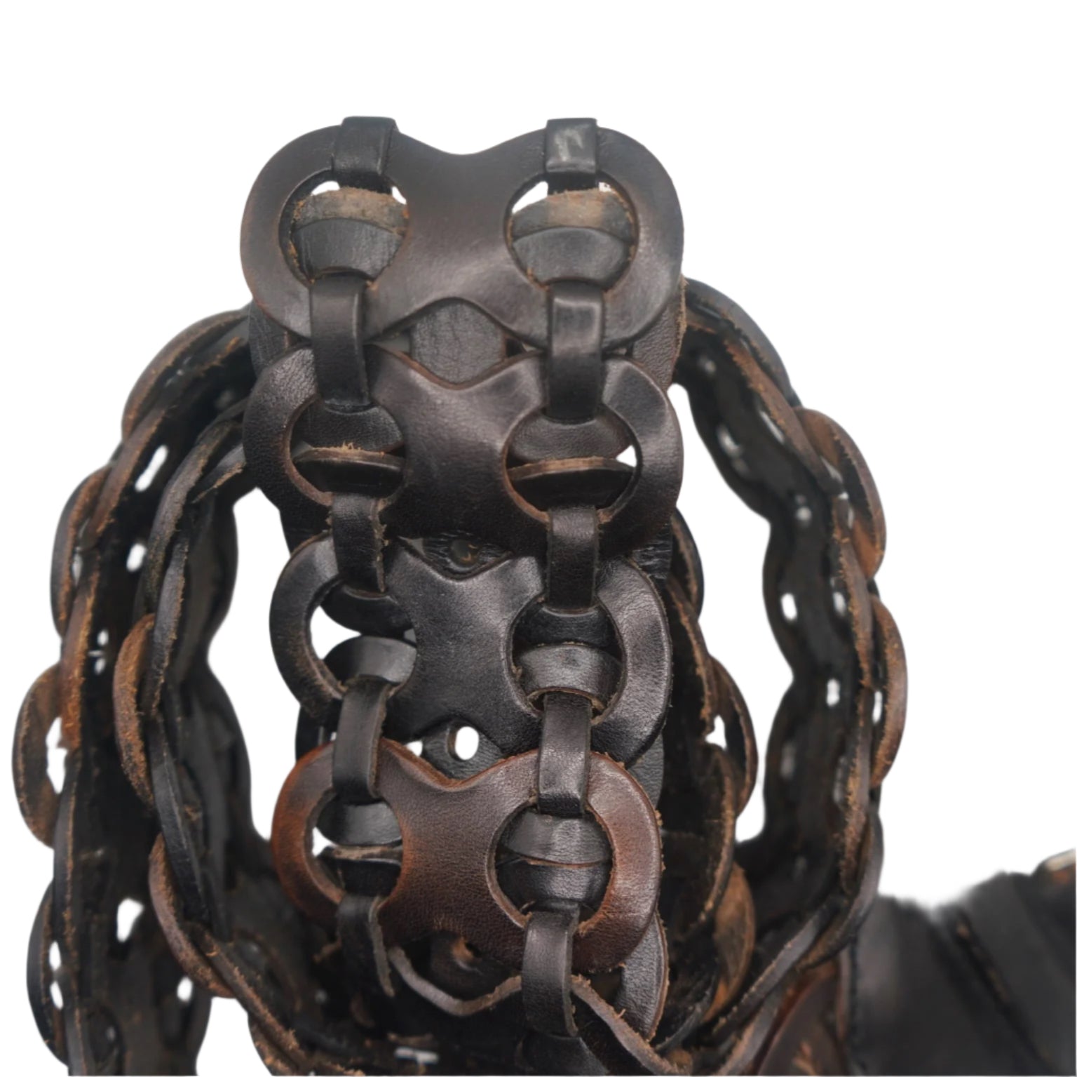 A close-up view of the intricate woven design of a vintage black leather belt. The interlocking loop pattern is highlighted from an overhead angle, showcasing the smooth texture of the leather and the contrasting brown stitching around the edges. The belt is coiled, with a section of the buckle partially visible on the right side.