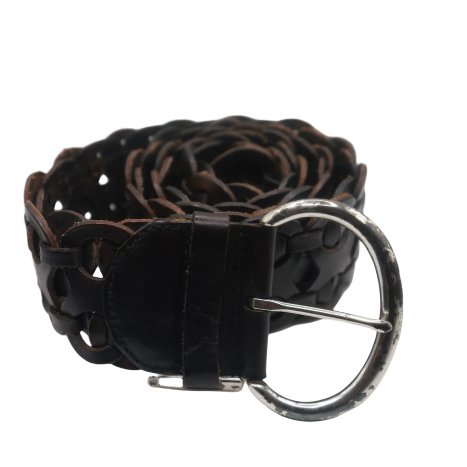 A close-up view of a vintage brown leather woven belt with a tarnished silver buckle. The belt is coiled, displaying its intricate, interlaced design that creates a unique textured appearance. The buckle is circular with a rustic finish, complementing the belt's aged look.