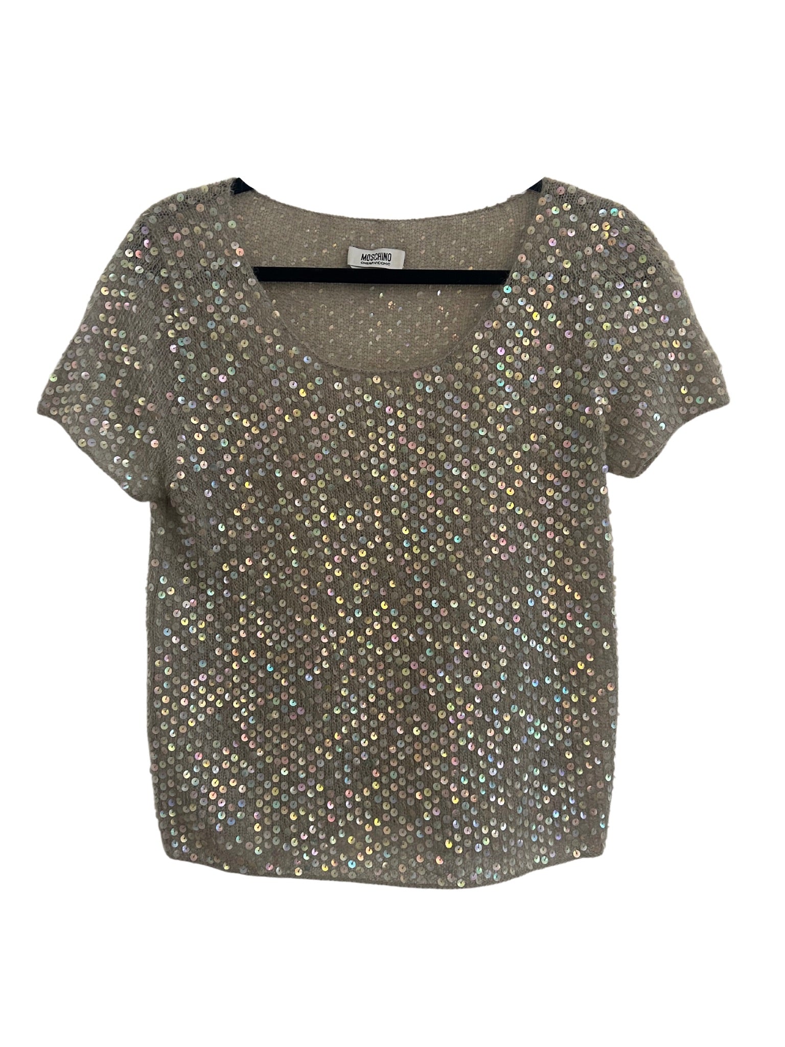 A Moschino sequin twin top displayed flat. The top is a gray knit garment entirely covered with shimmering, iridescent sequins that catch the light, creating a dazzling effect. It has a rounded neckline and short sleeves, with the sequins reflecting a variety of colors.